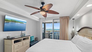 A hotel room with a bed, a ceiling fan, a TV, a dresser, and a view of the ocean. - Jetty view at Jetty East! One free beach chair set up daily. (Destin)