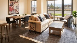 A modern living room with a beige sofa, a coffee table, and a dining area with a wooden table and chairs.