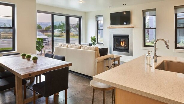 A modern kitchen with a large island, a fireplace, and a dining area with a sofa.