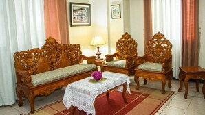 Uma sala de estar tradicional com dois sofás de madeira ricamente decorados, uma mesa pequena e um abajur.