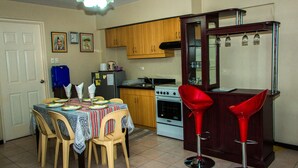 Uma cozinha compacta com armários de madeira, um fogão e uma área de jantar com mesa e cadeiras.