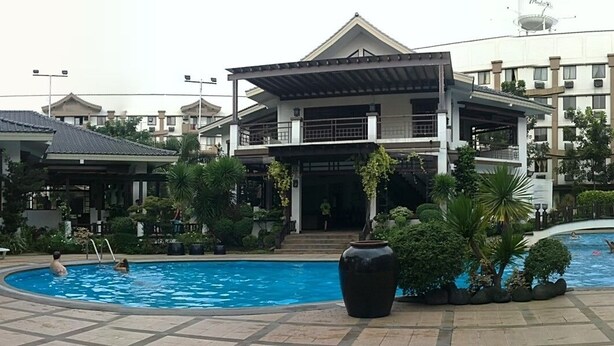 Um hotel com piscina, área coberta e construção tradicional.