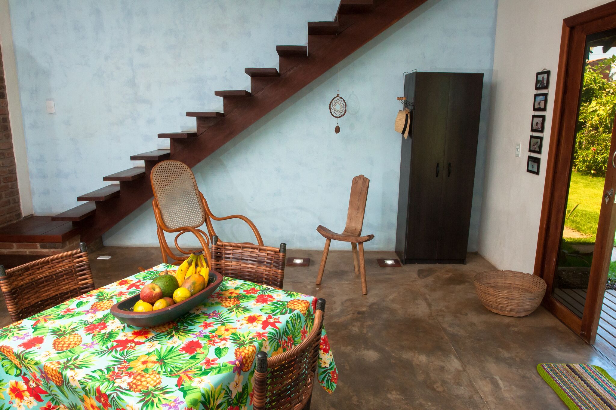 A dining area with a table set for two, a fruit bowl, and a staircase leading to an upper level.