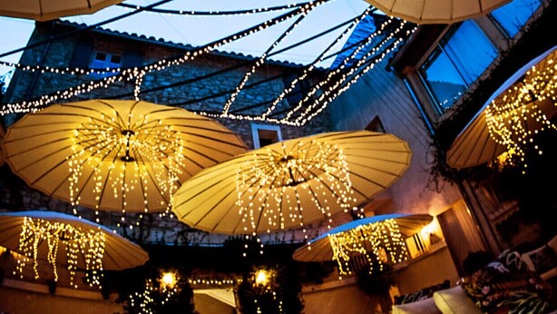 A spacious atrium with multiple large umbrellas adorned with string lights, creating a festive atmosphere. - Prestige 5 star villa  (Saint-Rémy-de-Provence)