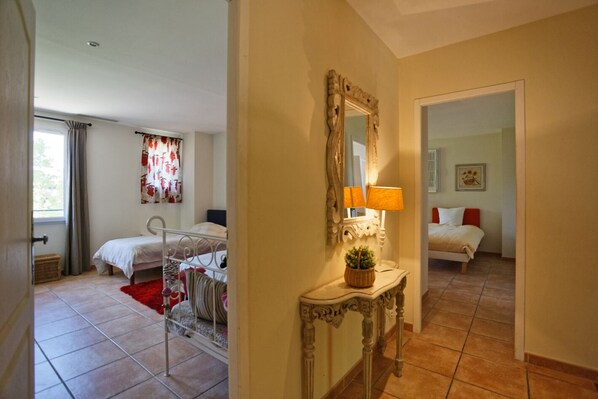 Quarto de hotel com cama, mesa de cabeceira com abajur, espelho e janela com cortinas.