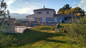 Une maison à deux étages dotée d’un balcon et d’un escalier en pierre menant à une zone abritée.