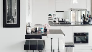A modern kitchen with a central island, a dining area with bar stools, and a large framed picture of a building. - 2 Rooms NEW Promenade des Anglais Amazing View (Nice)