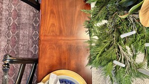 A dining table set with blue and white plates, gold-rimmed bowls, and white napkins tied with gold ribbons.