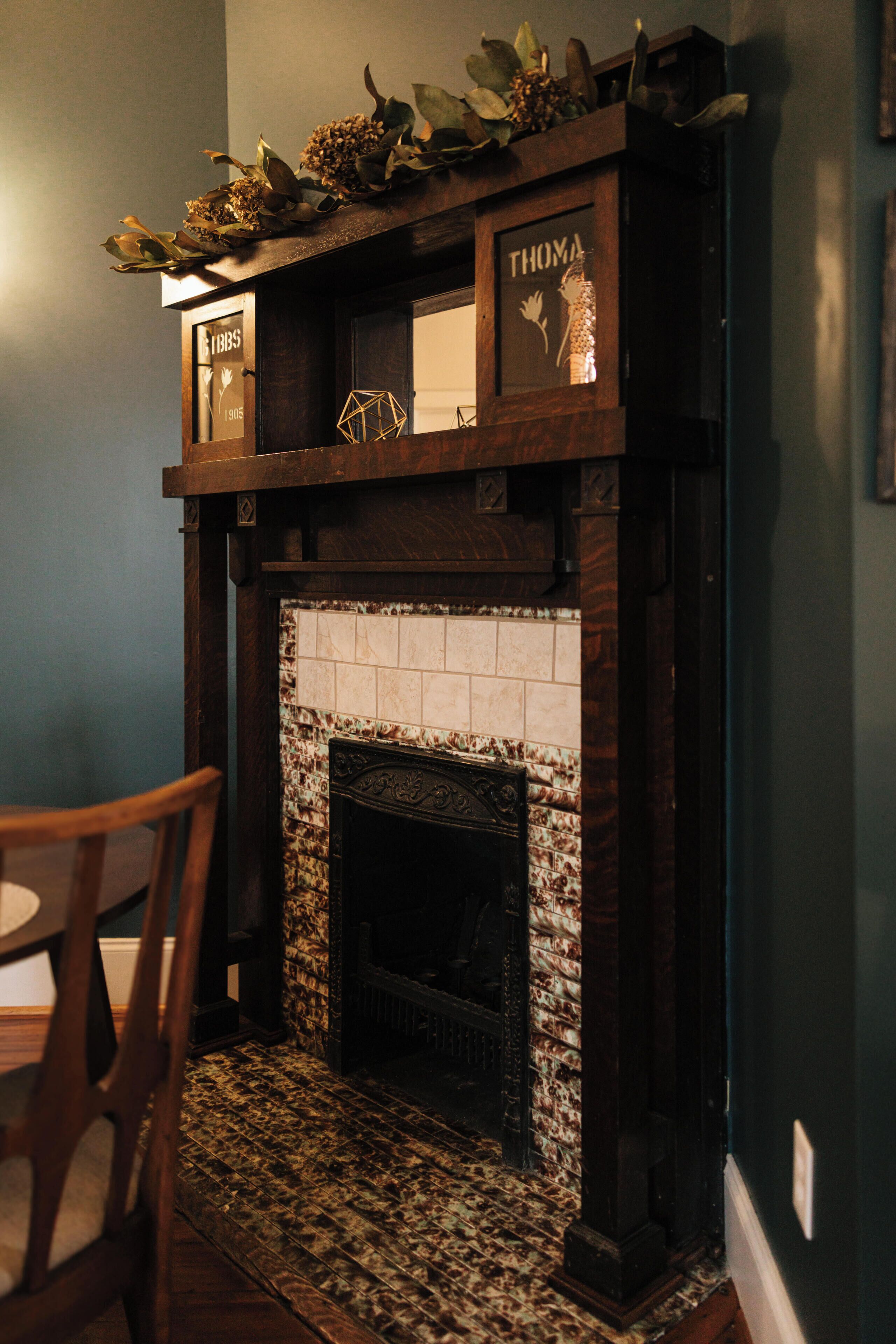 Una chimenea con detalles de azulejos, un repisa de madera y un estante decorativo superior.