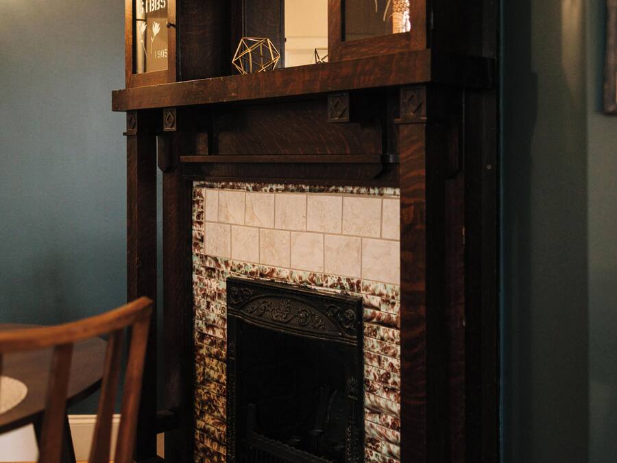 Una chimenea con detalles de azulejos, un repisa de madera y un estante decorativo superior.