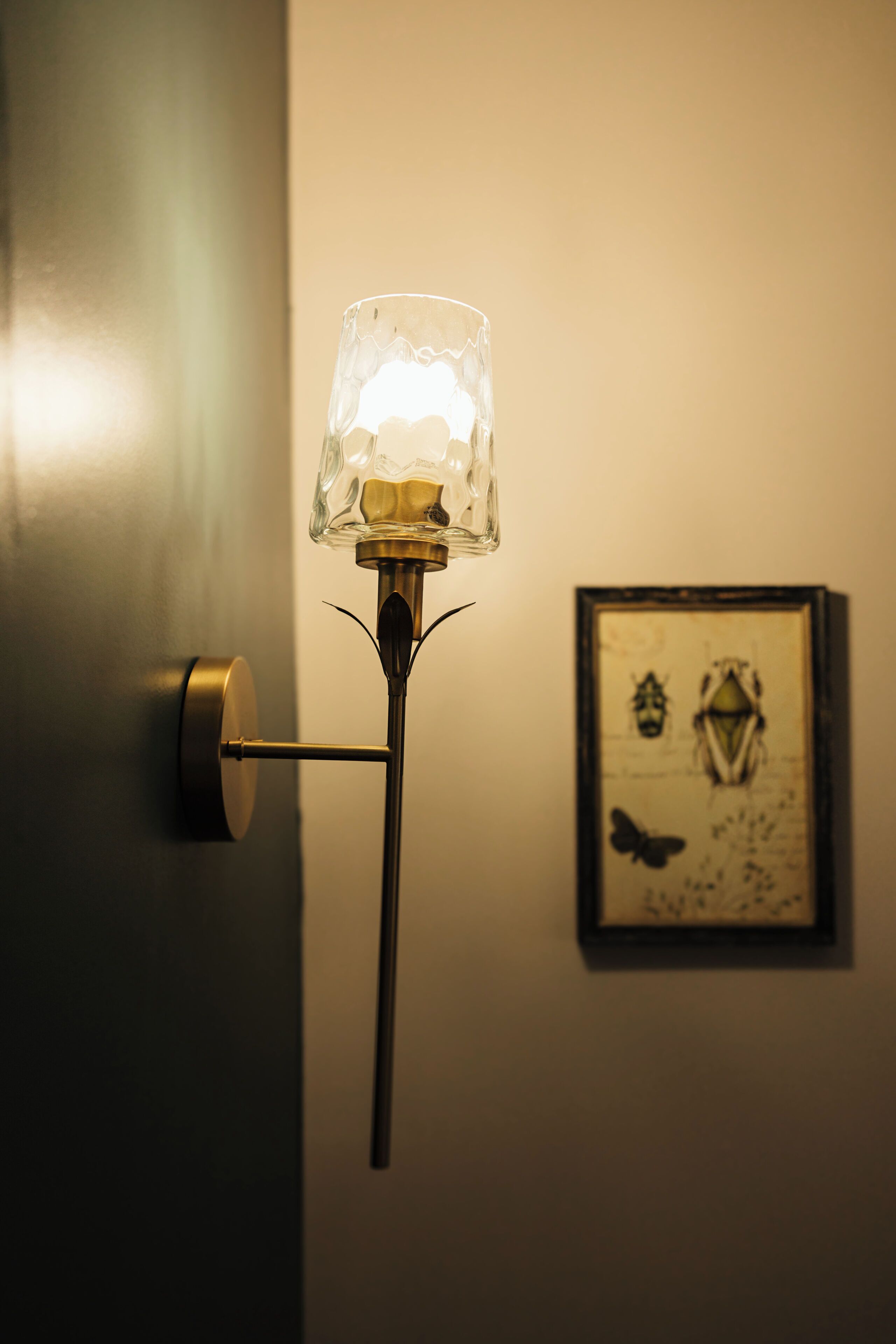 A wall-mounted light fixture with a glass shade and a metal stand.