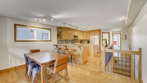 Eine moderne Küche mit Holzausstattung, einer zentralen Kochinsel und einem Essbereich mit Tisch und Stühlen.