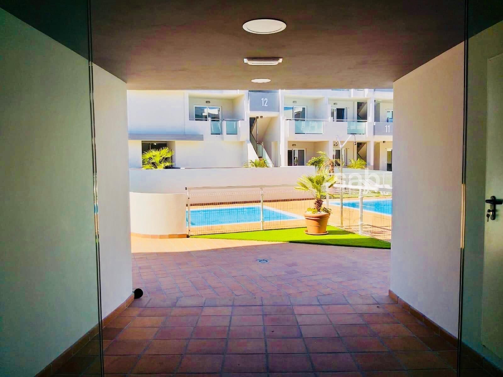 A corridor leading to a pool area with a view of a building with balconies and a number 12 sign.