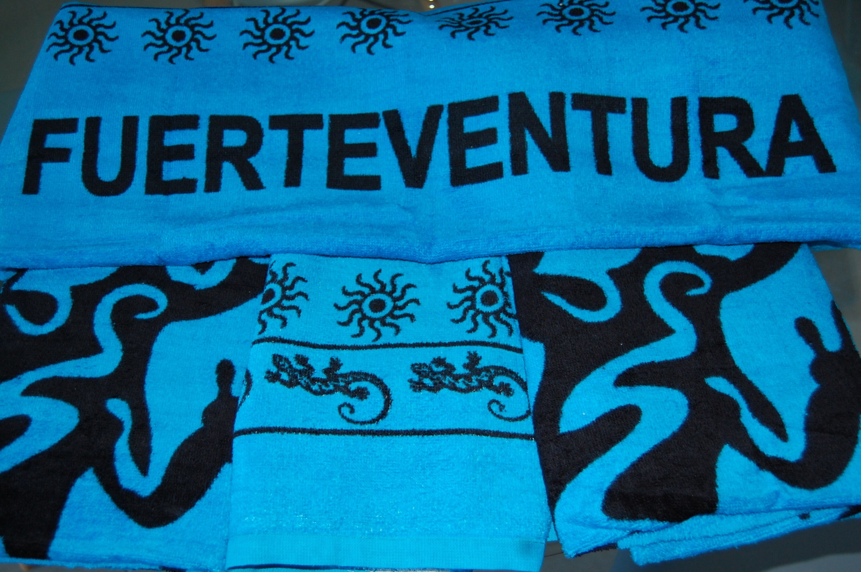 Een blauwe handdoek met zwarte patronen en de tekst "FUERTEVENTURA" er op gedrukt.