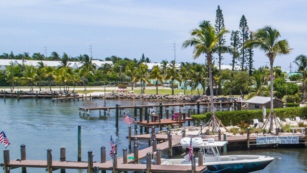 A marina with boats docked at wooden piers, surrounded by palm trees and a clear sky. - Keys Cove Villas - No 5 (Marathon)