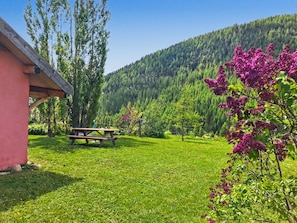A grassy area with a picnic table, a building, and a forested hillside. - Le troll: family chalet, valley views and skiing nearby (Névache)