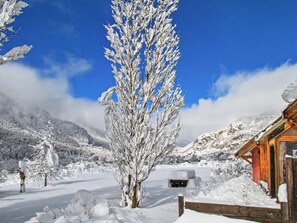 A snow-covered landscape with a wooden cabin, a snow-covered tree, and a clear blue sky. - Le troll: family chalet, valley views and skiing nearby (Névache)