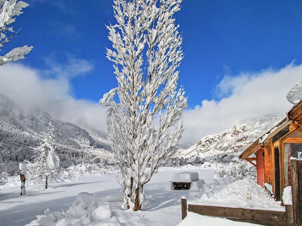 A snow-covered landscape with a wooden cabin, a snow-covered tree, and a clear blue sky. - Le troll: family chalet, valley views and skiing nearby (Névache)