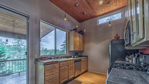 A modern kitchen with wooden cabinets, a large window, and a view of the outdoors. - Eagles Rest Dog Friendly | Soar, Slow Down, and Stay Above It All in Ruidoso (Ruidoso)