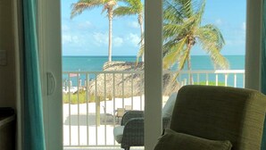 A room with a view of the beach, a chair, a remote control, and a flower on a table. - Keys Cove Villas - No 6 (Marathon)