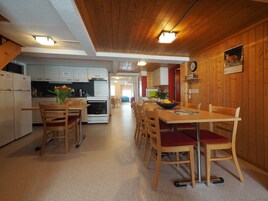 Una cocina con armarios de madera, un refrigerador blanco y una zona de comedor con sillas y mesa de madera.