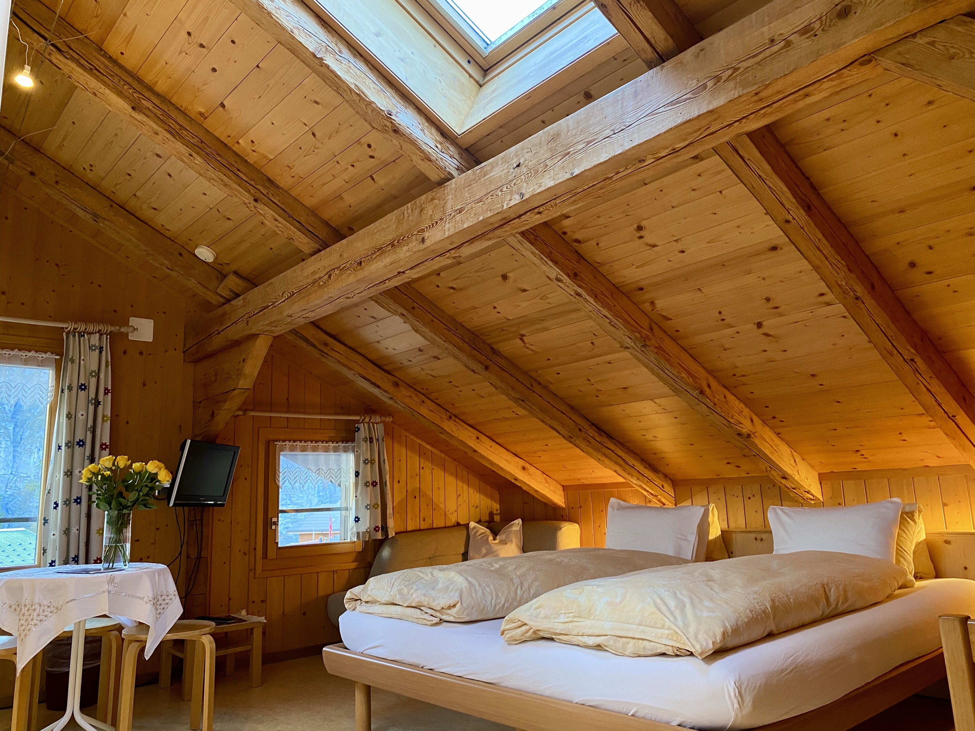 A wooden cabin with a loft bedroom, a dining area, and a TV.