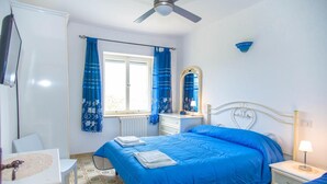A bedroom with a bed, a nightstand, a mirror, a window with curtains, and a ceiling fan. - La Terrazza di Laurino (Laurino)