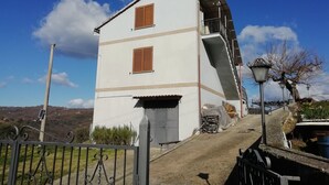 A white two-story building with brown shutters, a metal gate, and a paved path leading to it. - La Terrazza di Laurino (Laurino)