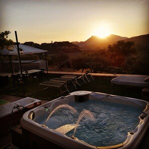 A hot tub with water jets, surrounded by outdoor furniture and a table under a canopy, with a sunset and mountains in the background. - La Terrazza di Laurino (Laurino)