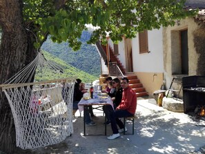 A group of people dining outdoors with a hammock and a barbecue grill. - La Terrazza di Laurino (Laurino)