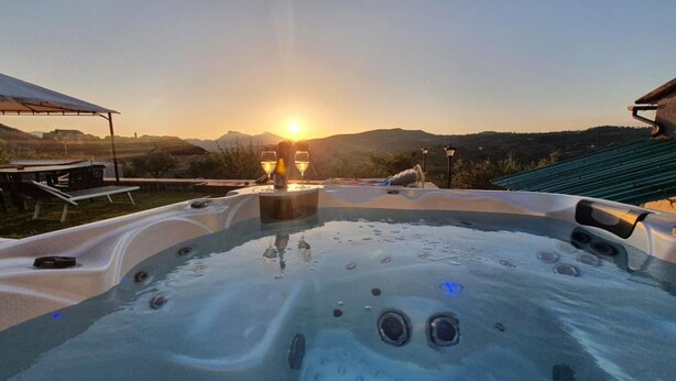 A hot tub with a sunset view, surrounded by outdoor furniture and a pergola. - La Terrazza di Laurino (Laurino)