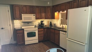 A kitchen with wooden cabinets, a white stove, a microwave, a refrigerator, and a sink. - Village of Elk Rapids Walk to Beach (Elk Rapids)