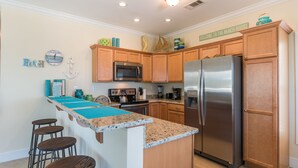 A kitchen with wooden cabinets, a stainless steel refrigerator, a microwave, and a granite countertop. - Keys Cove Villas - No 8 (Marathon)