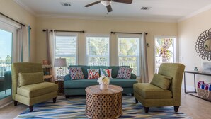 A living room with a sofa, two armchairs, a coffee table, and a view of the outdoors through large windows. - Keys Cove Villas - No 8 (Marathon)