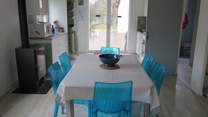 A dining area with a table set for four, surrounded by blue chairs. - 004 - Relaxation and rest in this house 2 steps from the ocean (SOULAC SUR MER)