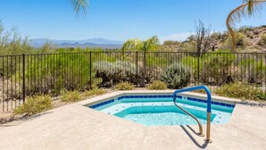 Une piscine bordée de carreaux bleus, entourée d’une terrasse en béton et d’une clôture en métal.