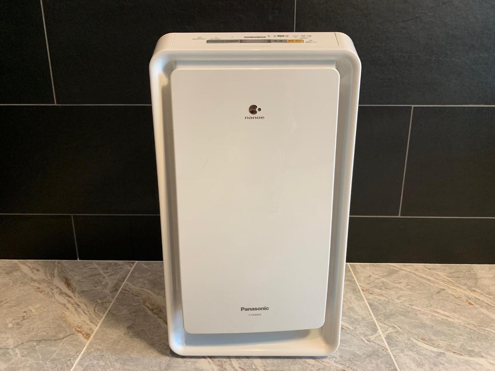 Un refrigerador Panasonic en una cocina con paredes de baldosas oscuras.