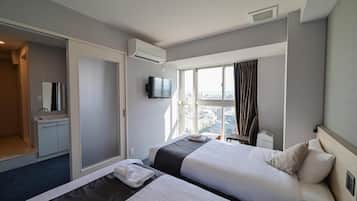 Une chambre d’hôtel avec deux lits, une télévision, une fenêtre avec des rideaux et une vue sur la ville.