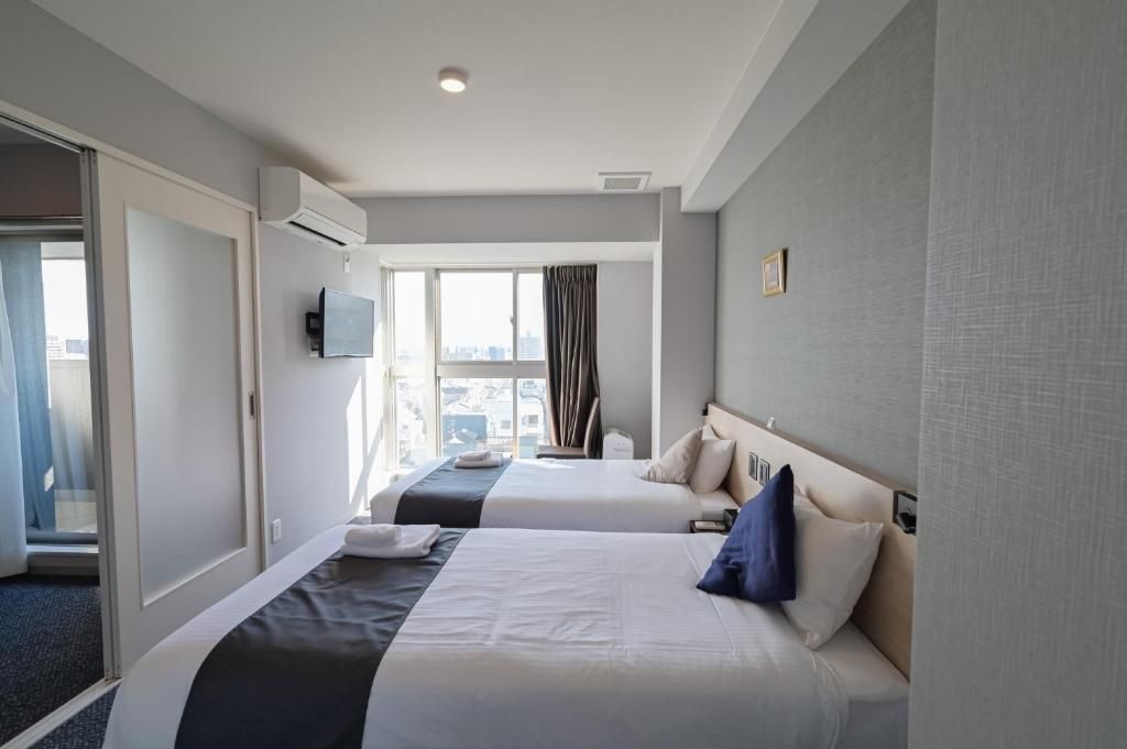 Une chambre d’hôtel avec deux lits, une télévision et une fenêtre avec des rideaux.