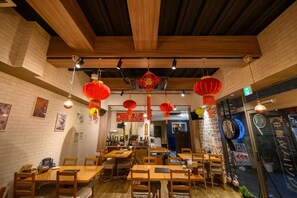 A restaurant interior with wooden tables and chairs, hanging red lanterns, and a brick wall. - Hotel State Tennoji - Hostel (Osaka)