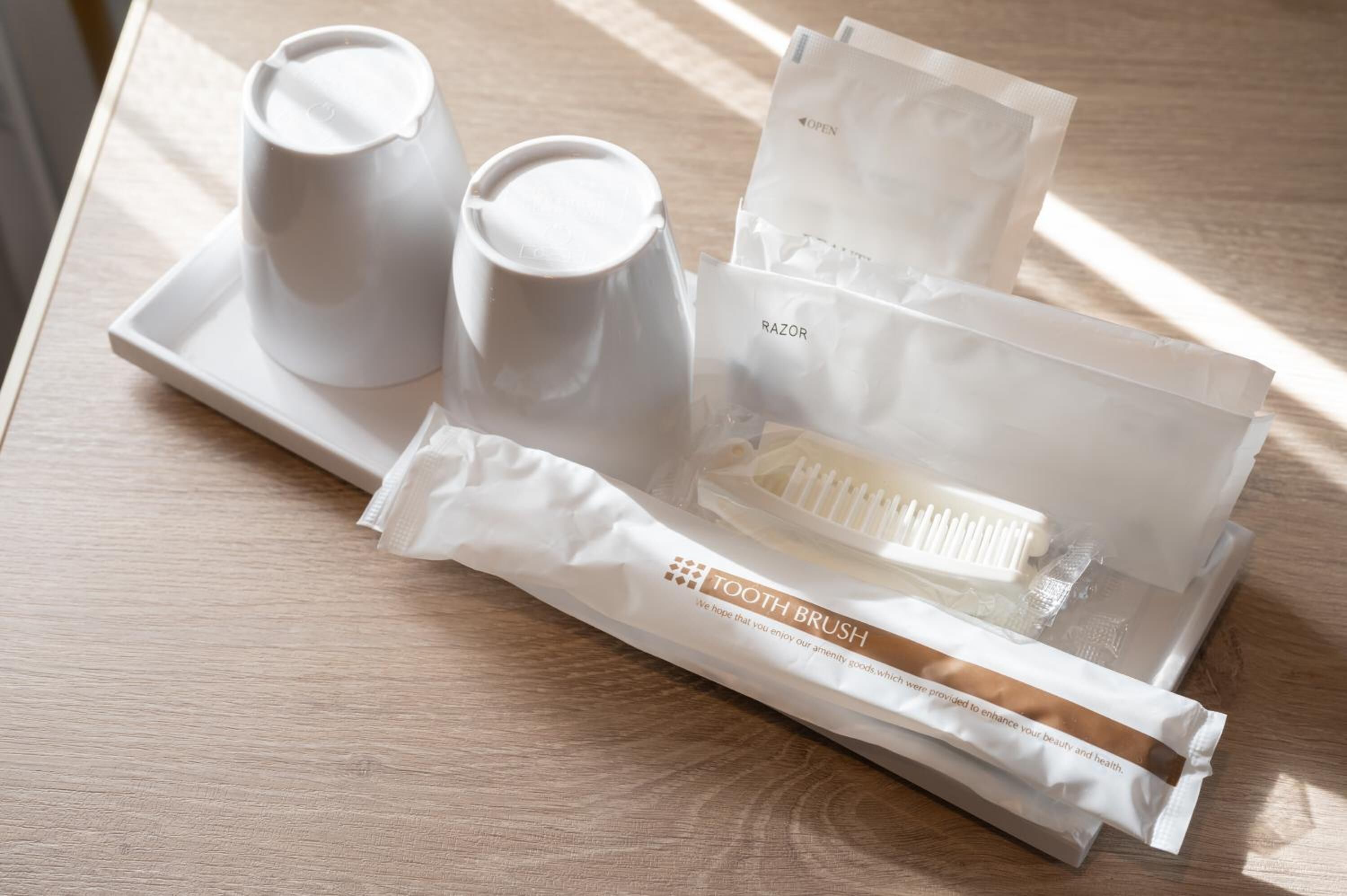 A tray with a toothbrush, toothpaste, and a razor on a wooden table.