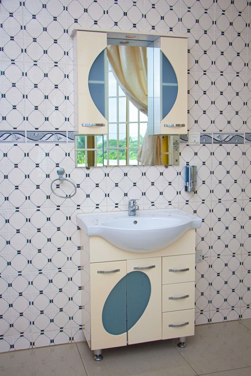 Een badkamer met een wit wastafelmeubel, een spiegel en een kastje met blauwe accenten.