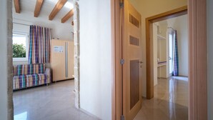 A hallway with a wooden door, a bench with striped cushions, and a window with a curtain. - WePuglia - Residence Cala Paura - Apt. Vecchio Frack (Polignano A Mare)