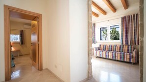 A room with a wooden door, a bench with colorful cushions, and a window with curtains. - WePuglia - Residence Cala Paura - Apt. Vecchio Frack (Polignano A Mare)