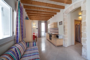 A modern interior with a wooden ceiling, a striped sofa, a kitchen area, and a stone wall.