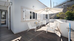 A covered outdoor area with a table, chairs, and an umbrella. - WePuglia - Residence Cala Paura - Apt. Vecchio Frack (Polignano A Mare)