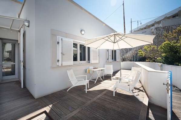 A covered outdoor area with a table, chairs, and an umbrella.