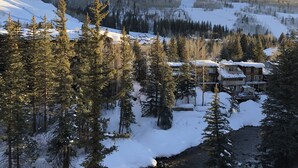 A snow-covered mountain landscape with a lodge featuring multiple buildings and a ski lift in the background.