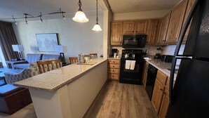 A compact kitchen with wooden cabinets, a microwave, a stove, and a refrigerator.