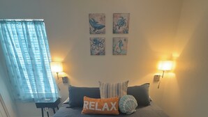 Une chambre à coucher avec un lit, deux lampes fixées au mur, une petite table et une chaise.